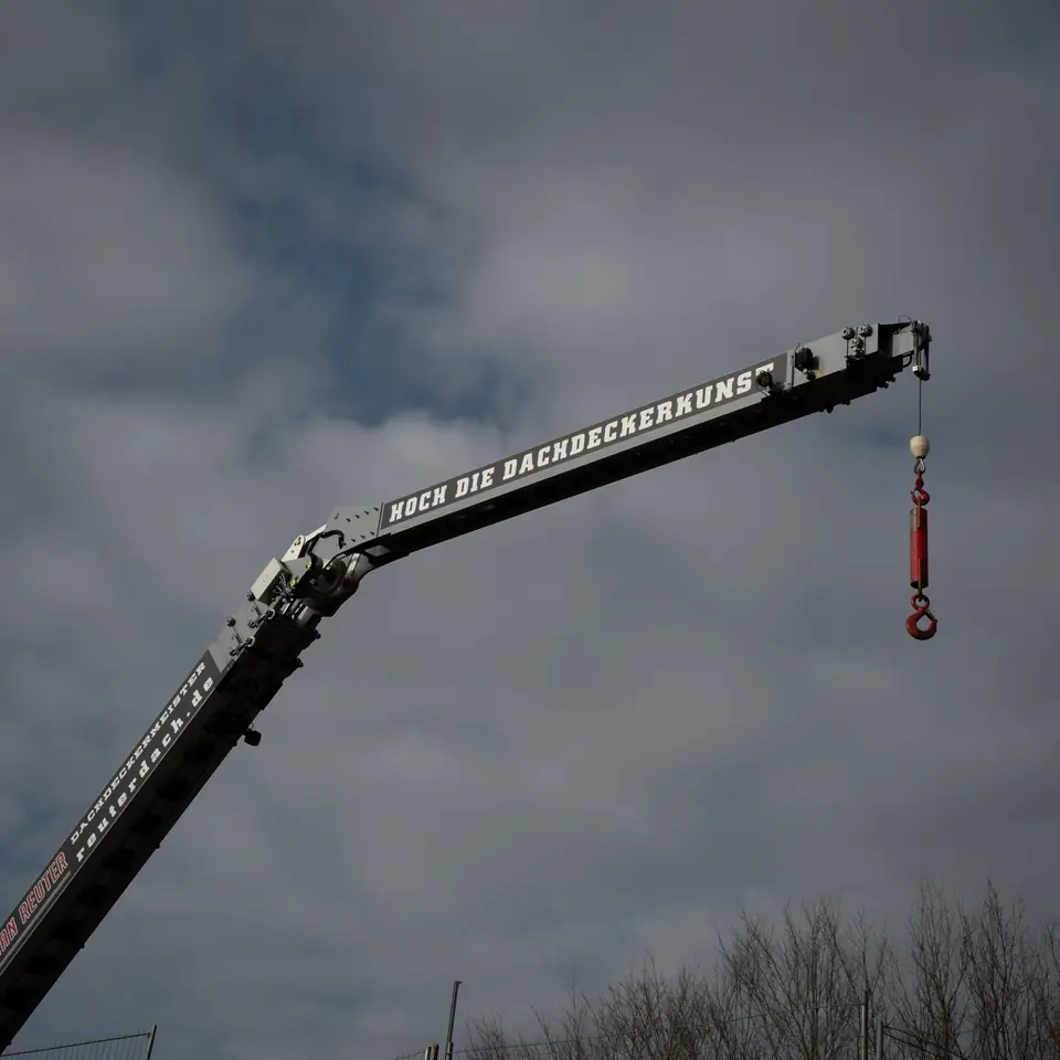 Kranausleger mit Last vor bewölktem Himmel